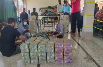 Workers recording and stacking the neatly wrapped bundles of sorted donation money.