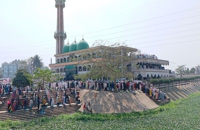 A crowd gathered on stepped embankments in front of the mosque during daylight.